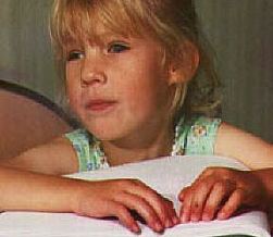 Young girl reading braille.